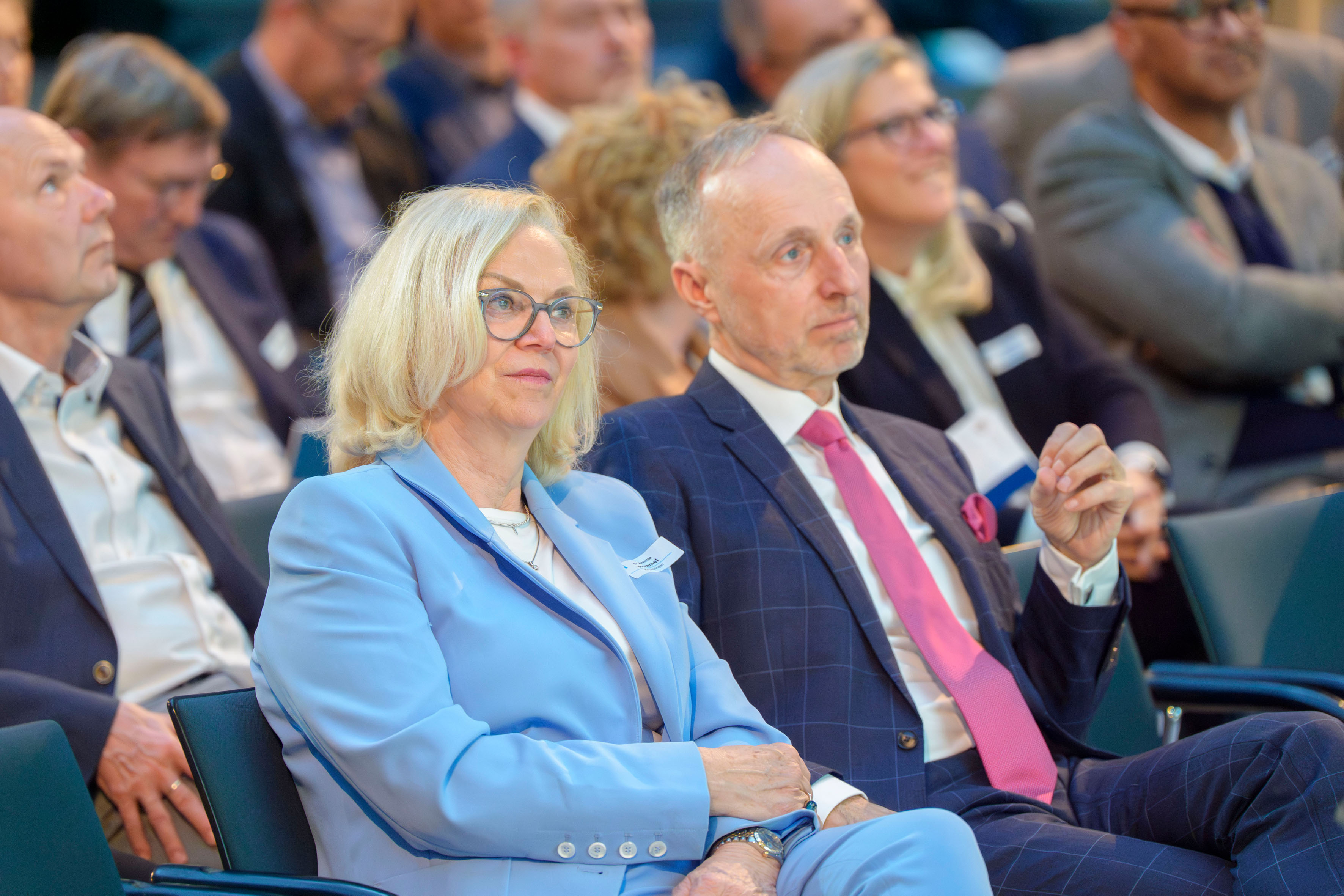 Dr. Annette Rommel und Dr. Stephan Hofmeister hören in der ersten Reihe des Publikums den Vorträgen zu.