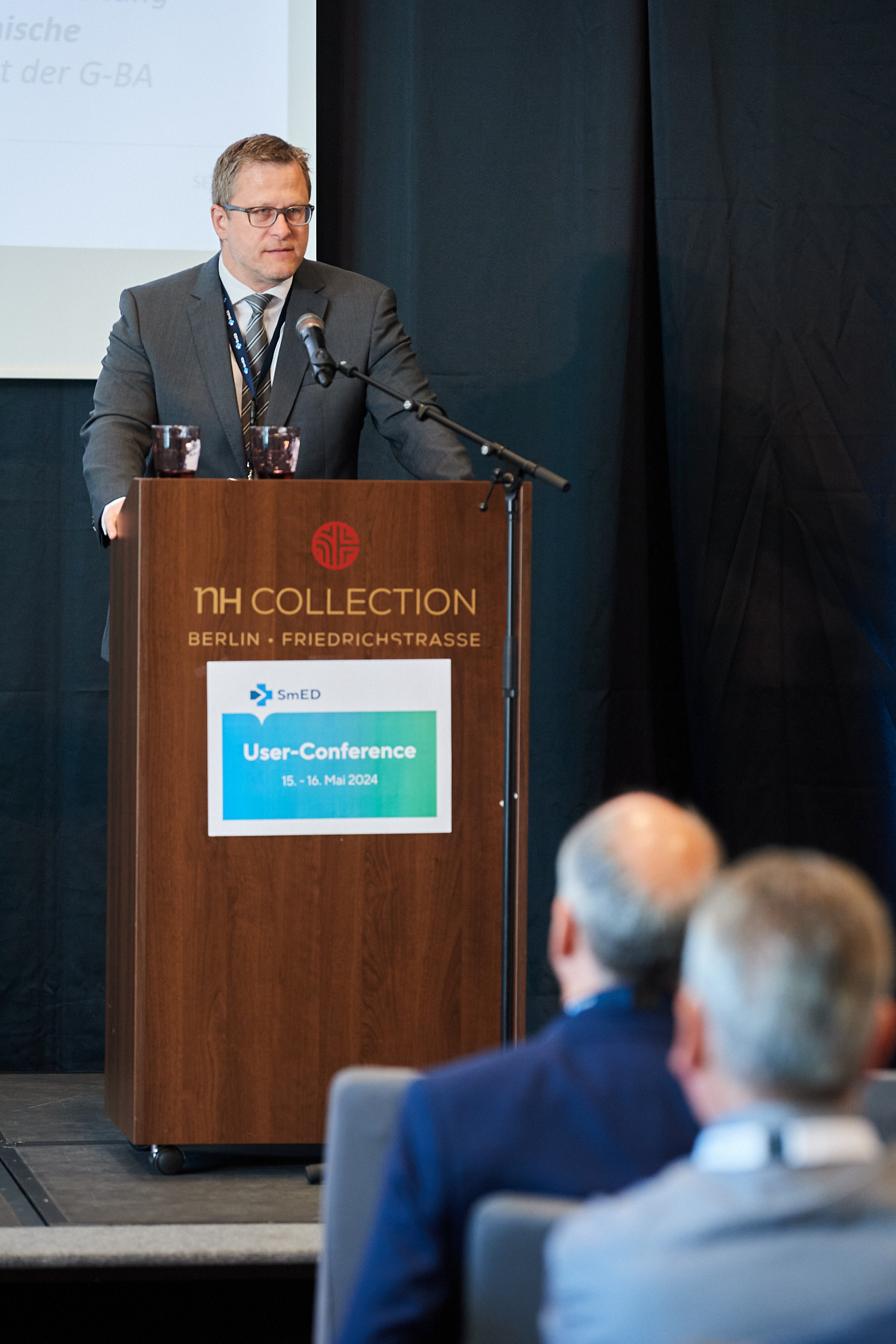 Ein Mann spricht am Mikrofon vor den Konferenzteilnehmenden.