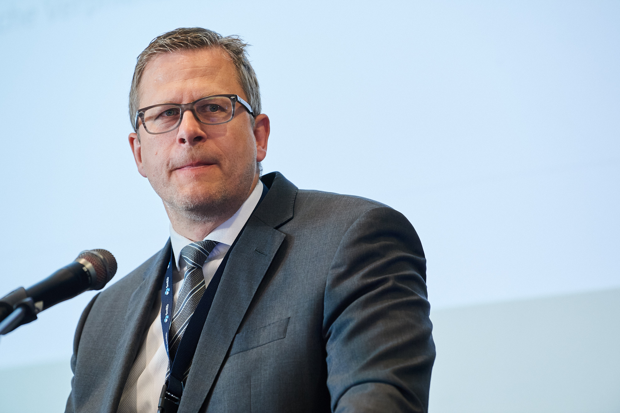 Ein Mann steht am Mikrofon und hält einen Vortrag.