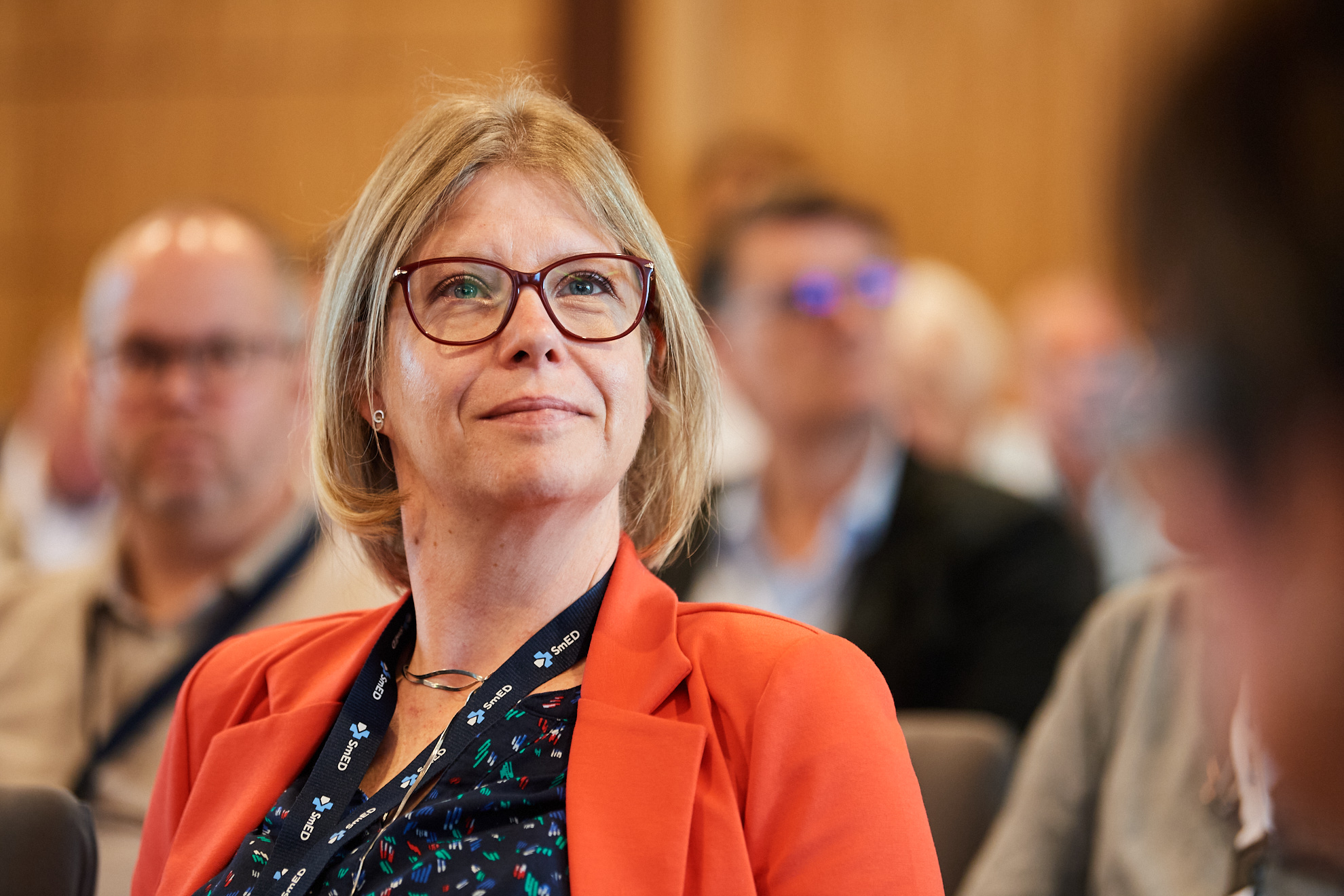 Eine Frau im Publikum hört einem Vortrag zu.
