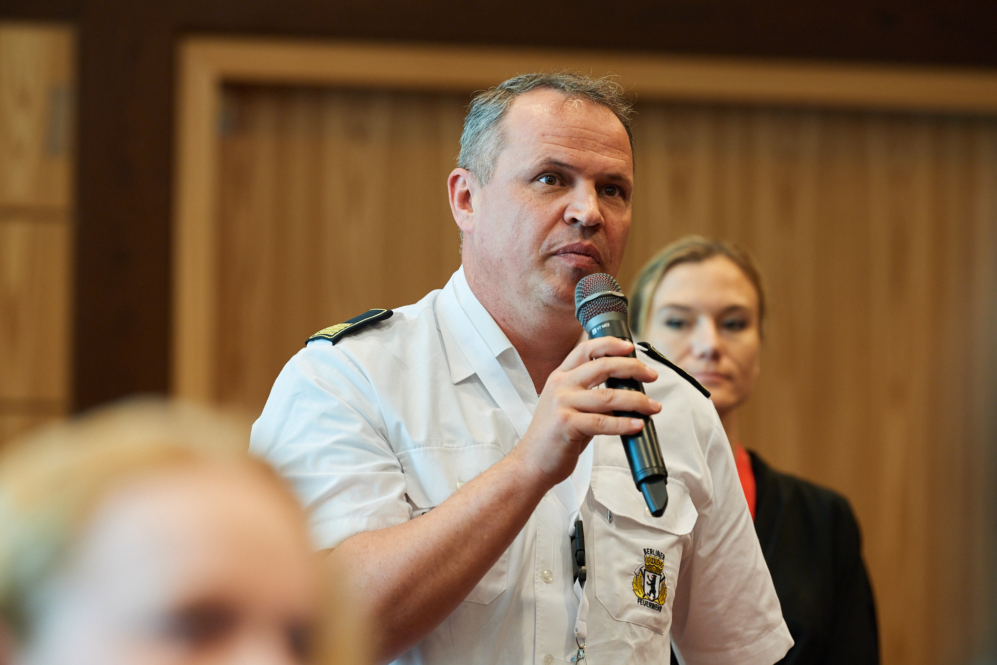 Ein Mitarbeiter der Berliner Feuerwehr spricht ins Mikrofon.