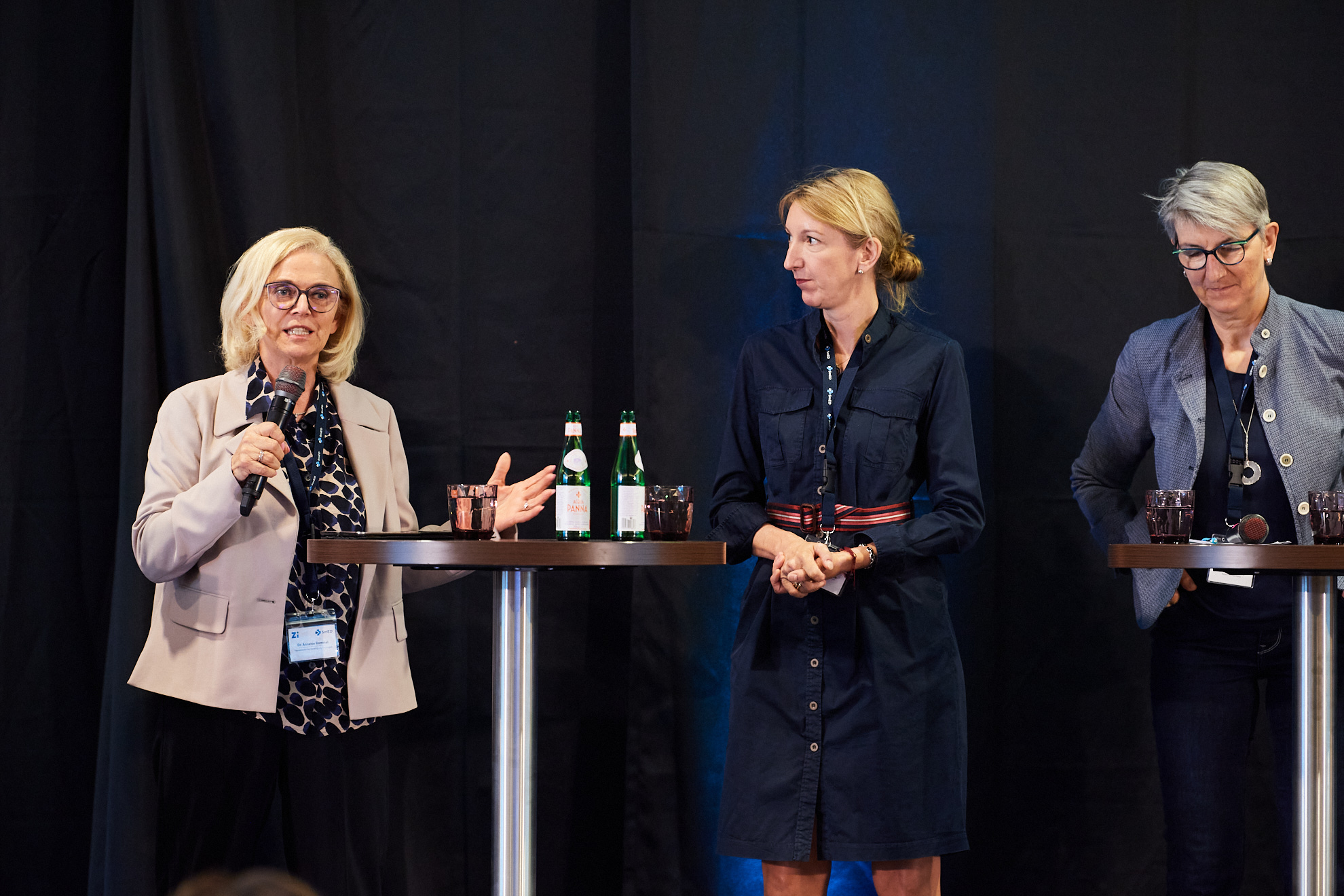 Drei Frauen befinden sich auf der Bühne, eine spricht.