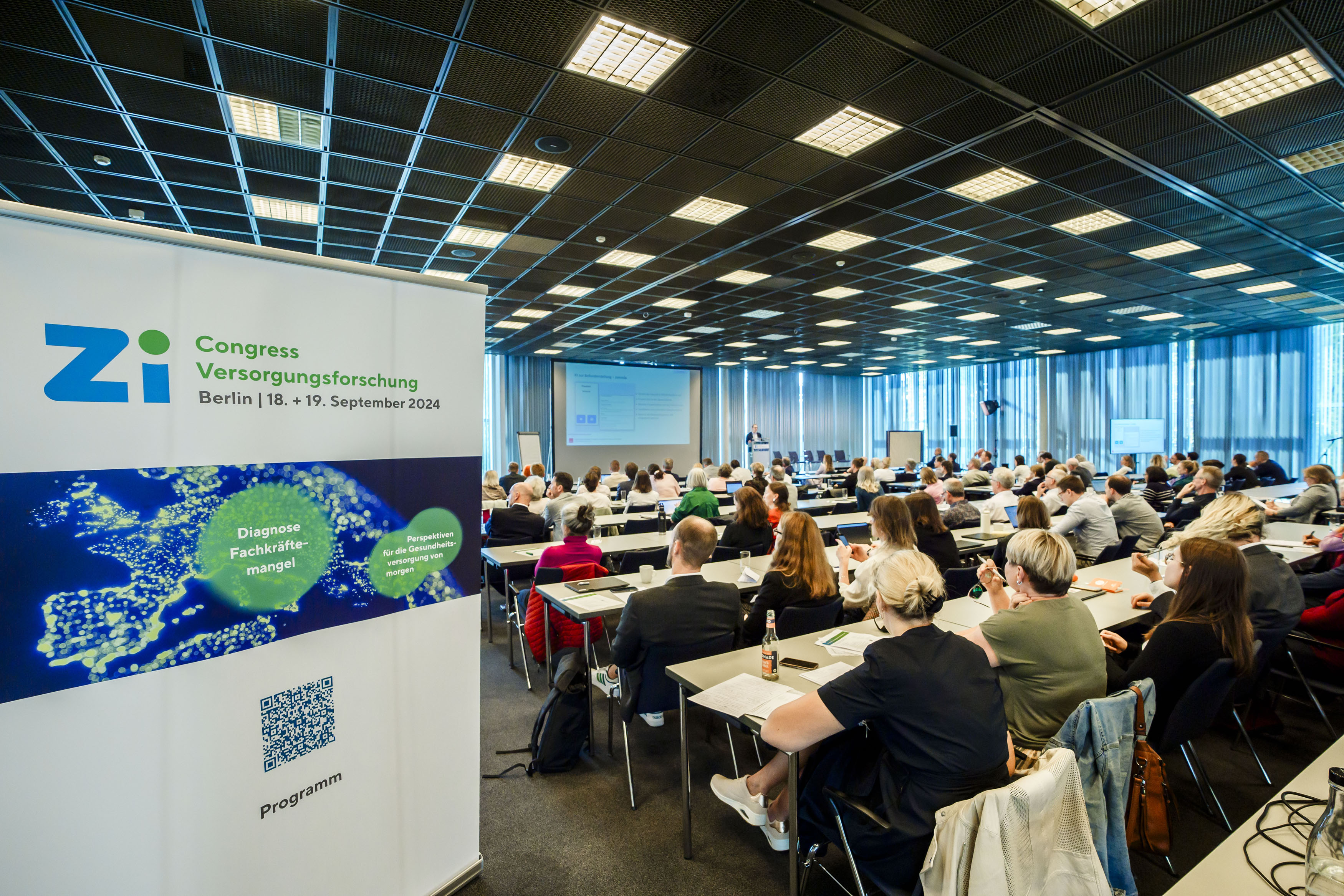 Tagungsraum mit Publikum von hinten fotografiert inklusive Roll-Up des Zi-Congresses