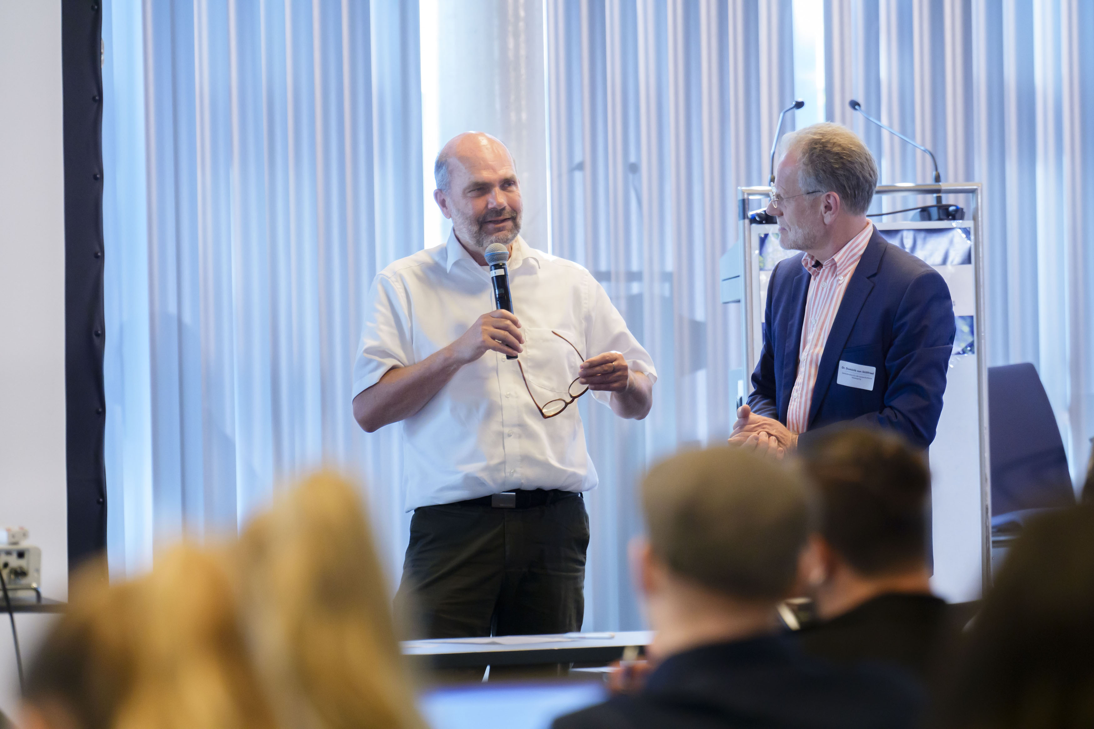 Prof. Dr. Reinhard Busse mit Handmikrofon neben Dr. Dominik von Stillfried