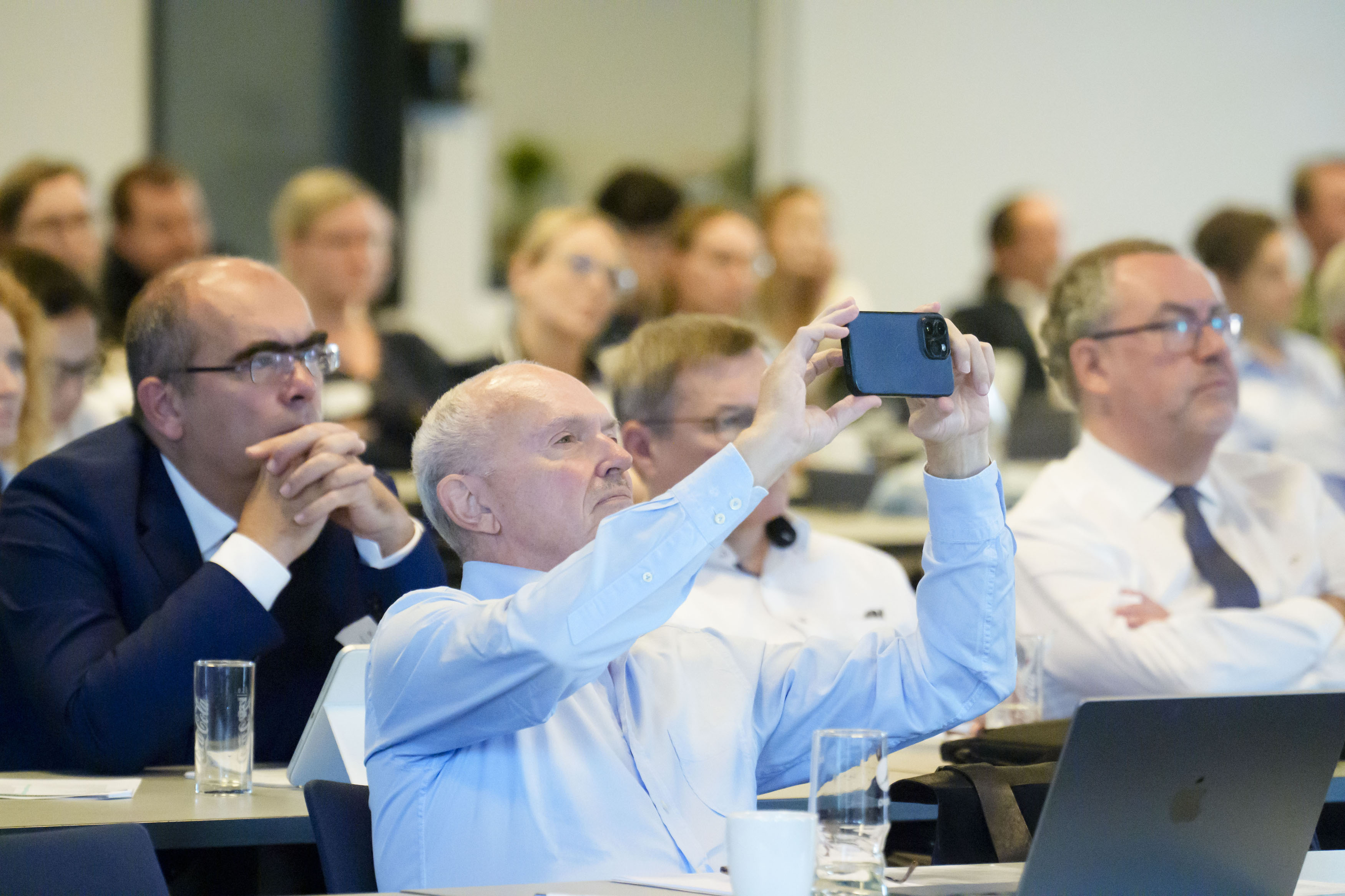 Publikumsgast fotografiert Vortragsfolien mit seinem Handy