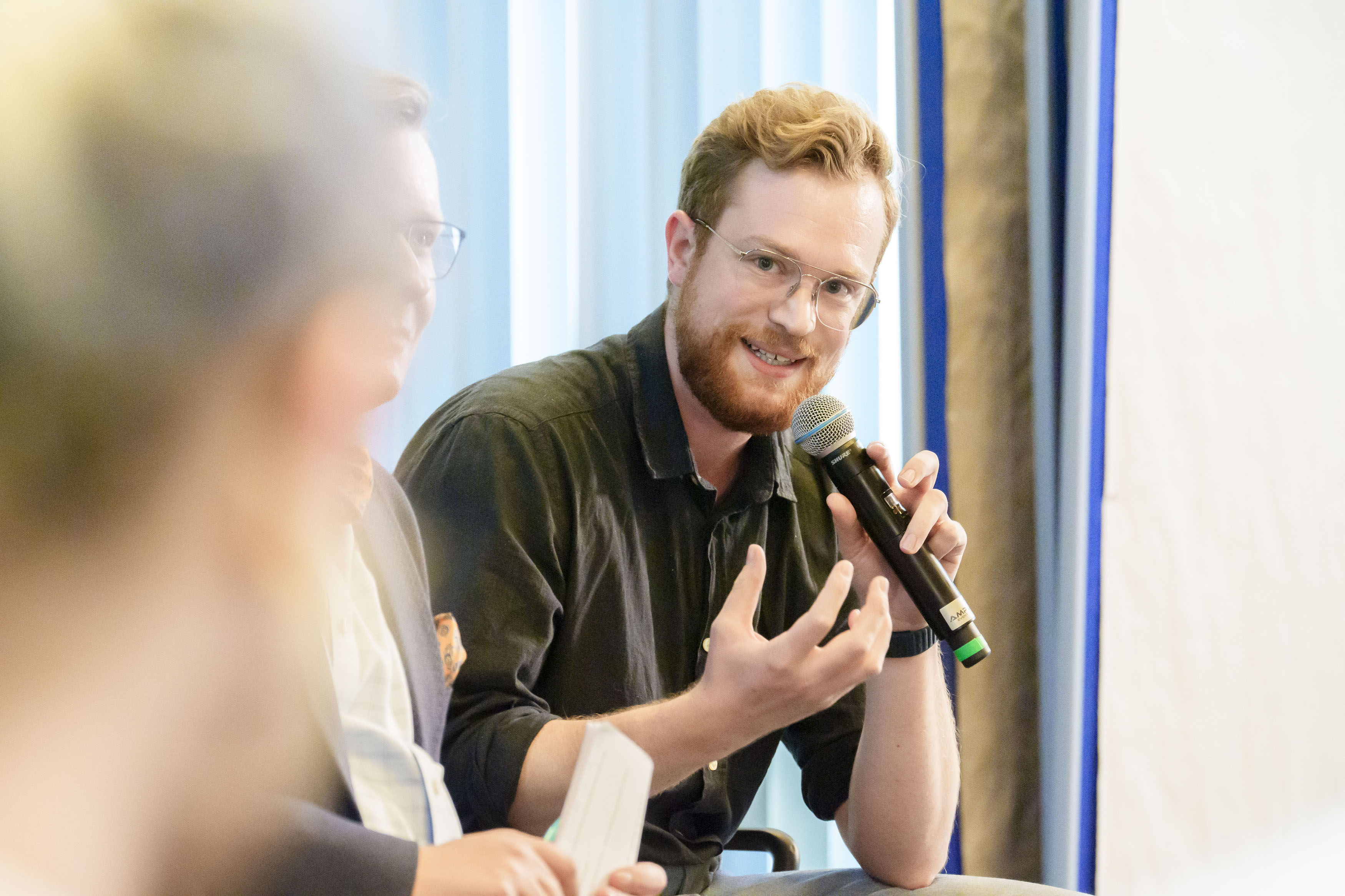 Podiumsteilnehmer mit Handmikrofon während seines Wortbeitrags
