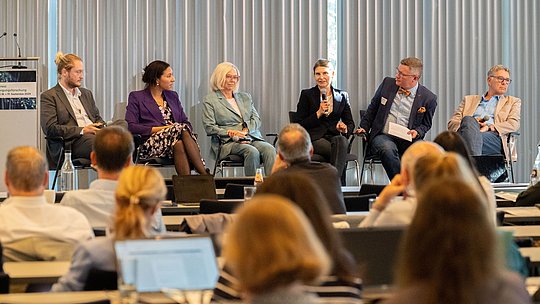 Weitere Podiumsdiskussion aus der Ferne mit den Köpfen des Publikums im Vordergrund