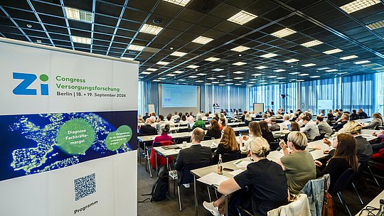 Tagungsraum mit Publikum von hinten fotografiert inklusive Roll-Up des Zi-Congresses