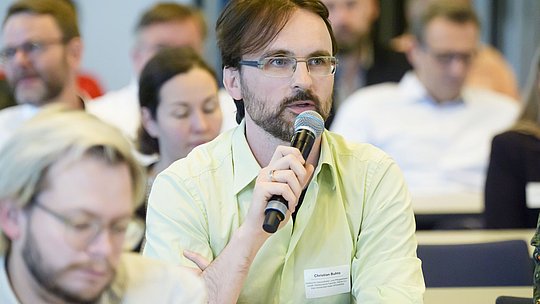 Teilnehmer stellt eine Frage mit Mikrofon im Publikum