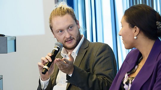 Podiumsgast mit Handmikrofon während seines Wortbeitrags