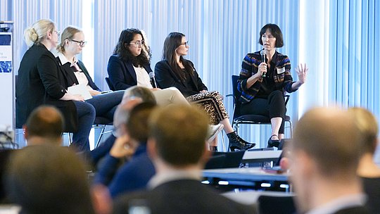 Podiumssituation aus der Ferne mit Publikum im Vordergrund