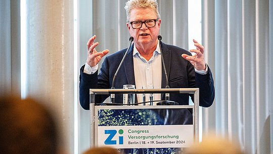 Redner am Podium spricht mit Gestik vor Publikum