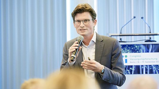 Redner mit Handmikrofon während eines Vortrags